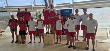 Gruppendfoto von Schwimmern auf Treppchen, Siegerposen mit Medaillen in der Hand.