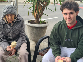 Eine ältere Frau und ein junger Mann sitzen nebeneinander und essen Eis.