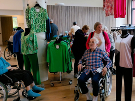 Eine Gruppe von Senioren in einem Bekleidungsgeschäft mit bunten Kleidungsstücken.
