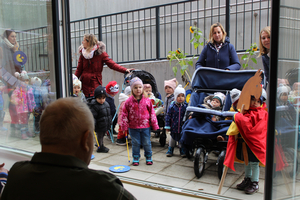 Eine Gruppe von Kindern und Erwachsenen steht vor einem Fenster.