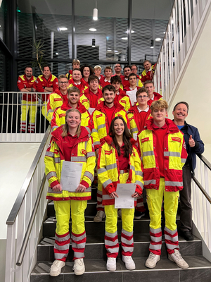 Gruppe von Rettungskräften in roten und gelben Uniformen auf einer Treppe.