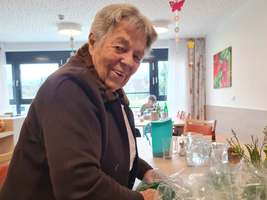 Eine lächelnde Frau packt frische Kräuter in eine Tüte.