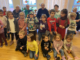 Eine Gruppe von Kindern steht in der Mitte, umringt von älteren Personen.