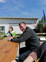 Ein älterer Mann sitzt an einem Tisch und lächelt.