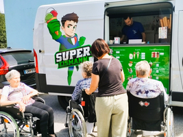 Eiswagen mit Personen im Rollstuhl, die Eis bestellen.