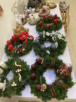 Mehrere dekorative Adventskränze mit unterschiedlichen Kerzen und Weihnachtsverzierungen.