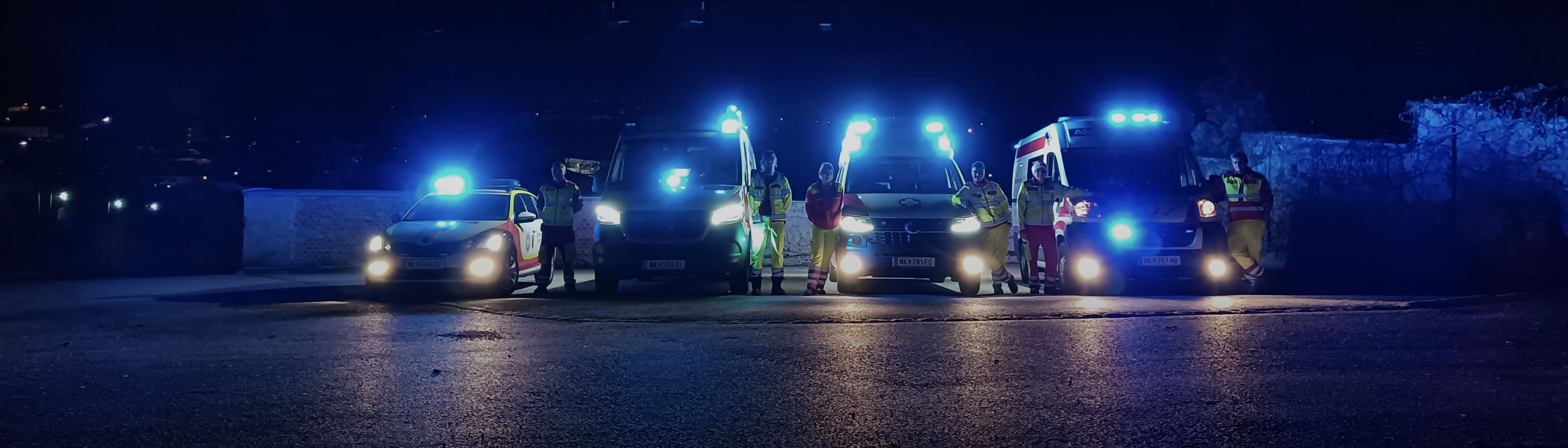 Rettungsfahrzeuge und Einsatzkräfte mit eingeschaltetem Blaulicht in der Nacht.