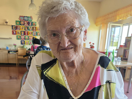 Ältere Dame bindet Lavendelsträuße in einem hellen Raum.