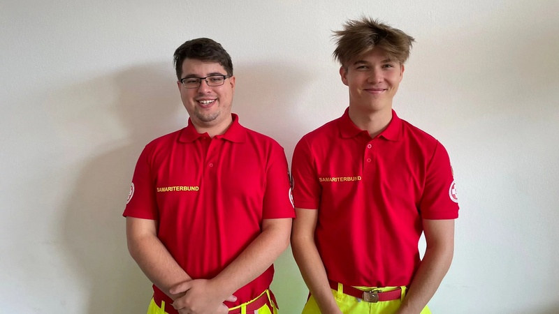 Zwei lächelnde Männer in roten Poloshirts des Samariterbundes stehen nebeneinander.