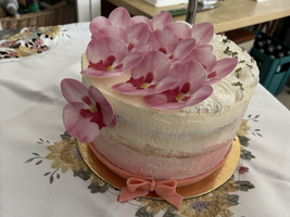 Eine Torte mit rosa Orchideenblüten und einer pinken Schleife.