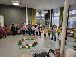 Kinder führen ein Programm in einem Gemeinschaftsraum mit Senioren auf.