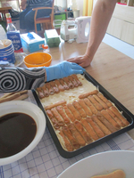 Zwei Hände bereiten ein Dessert mit langen Bisquitstangen in einer Backform vor.