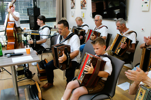 Eine Gruppe von Menschen spielt gemeinsam auf Harmonikas in einem Raum.