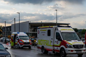 Zwei Rettungswagen stehen an einer Unfallstelle unter bewölktem Himmel.