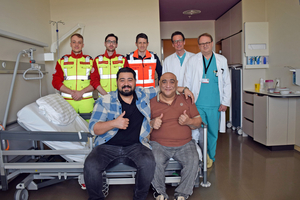 Rajko Nikolic und sein Sohn sitzen gemeinsam im Krankenhaus, hinter ihnen stehen drei Sanitäter und zwei Ärzte.