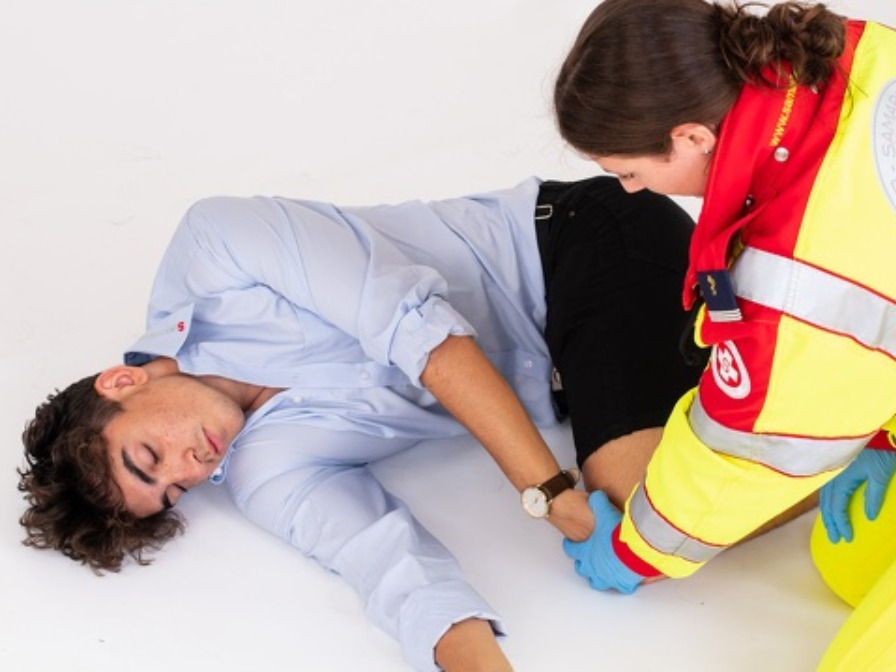 Ein Sanitäter behandelt einen verletzten jungen Mann am Boden.